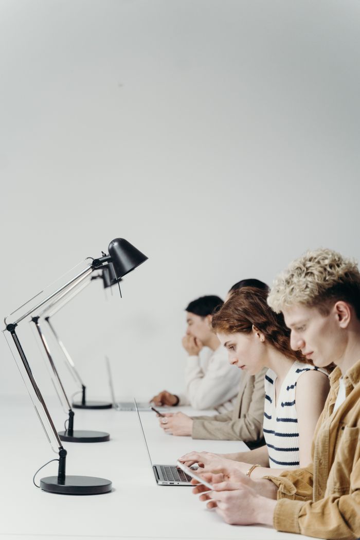 Group of young professionals using laptops at a modern office desk, emphasizing teamwork.